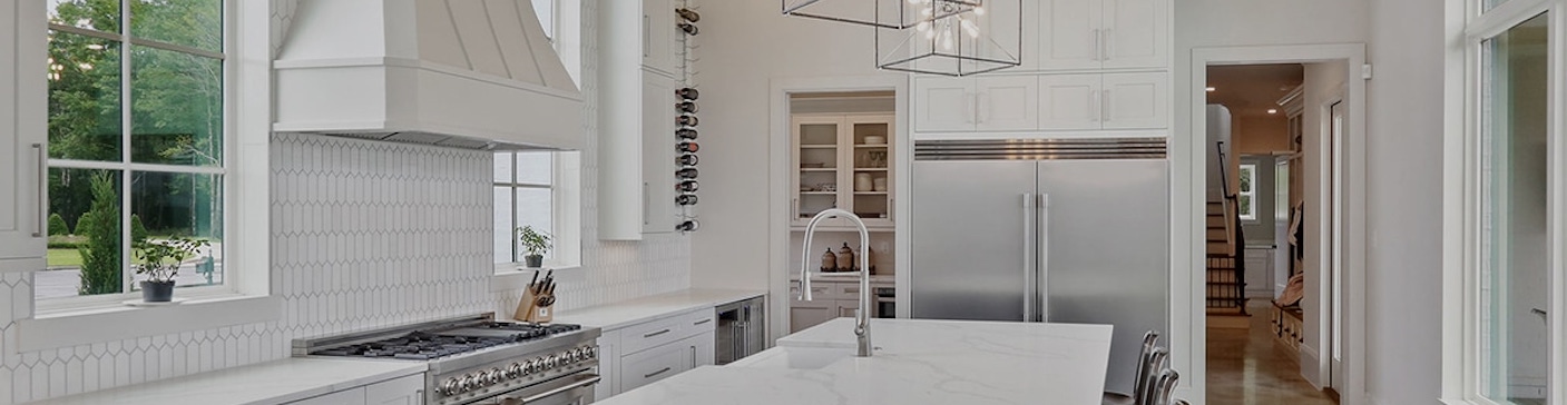 Kitchen with custom cabinetry, a stone island and integrated appliances